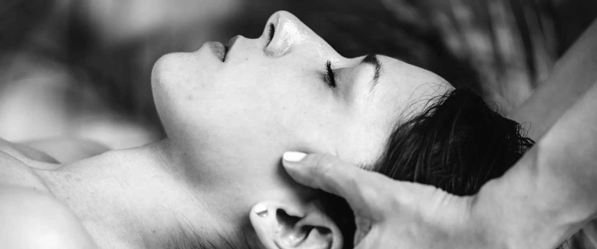 Händer som varsamt håller en patients huvud under en osteopatisk behandling